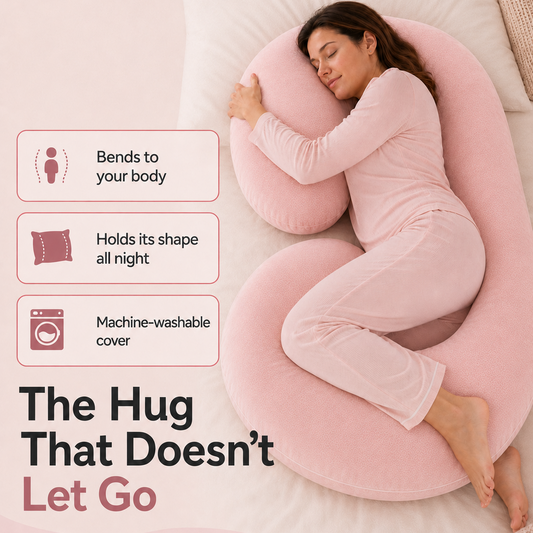 A woman in a pink pajama set reclines on a large pink U-shaped body pillow on a bed, with text callouts highlighting features like bending to the body, holding shape all night, and machine-washable cover.